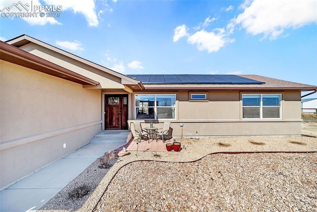 property entrance featuring solar panels and stucco siding