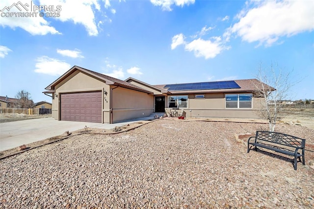 ranch-style home with an attached garage, driveway, solar panels, and stucco siding