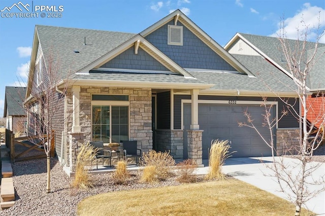 craftsman-style house featuring a garage, stone siding, concrete driveway, and roof with shingles