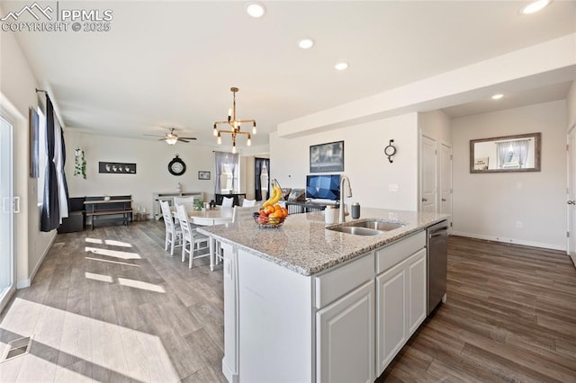 kitchen with open floor plan, a sink, stainless steel dishwasher, and wood finished floors