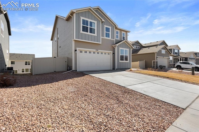 view of front of property featuring an attached garage, board and batten siding, fence, a residential view, and driveway