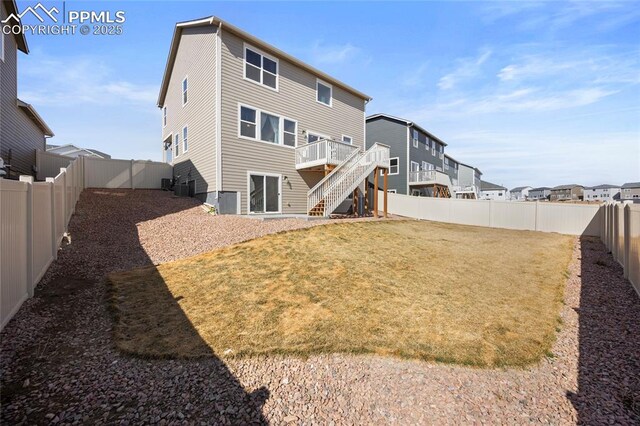 back of property with a lawn, a fenced backyard, a residential view, stairway, and a deck