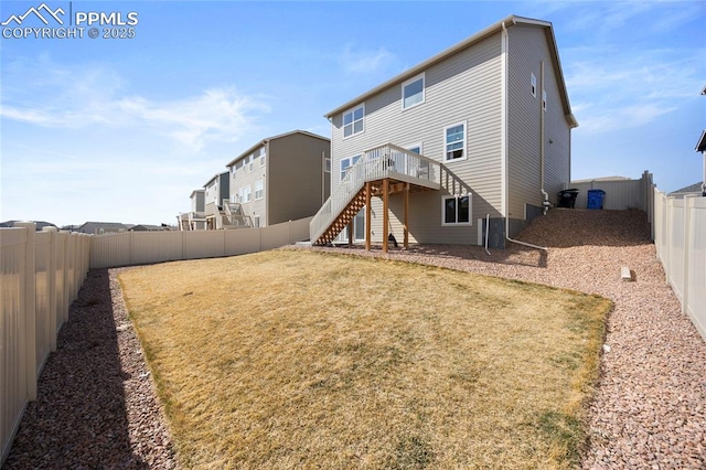 back of house featuring a fenced backyard, a lawn, stairway, and a wooden deck