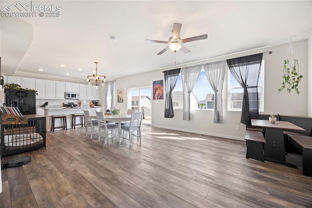 dining space with dark wood-style floors, recessed lighting, baseboards, and ceiling fan with notable chandelier