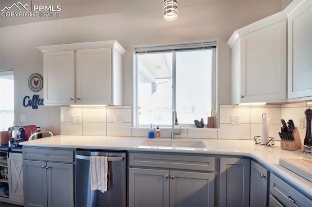 kitchen with a sink, white cabinetry, light countertops, dishwasher, and tasteful backsplash