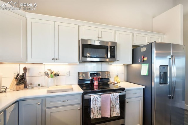 kitchen featuring appliances with stainless steel finishes, white cabinets, light countertops, and decorative backsplash