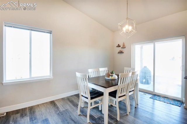 dining area featuring lofted ceiling, an inviting chandelier, wood finished floors, and baseboards