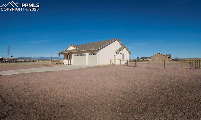 view of side of home featuring a garage, concrete driveway, fence, and stucco siding