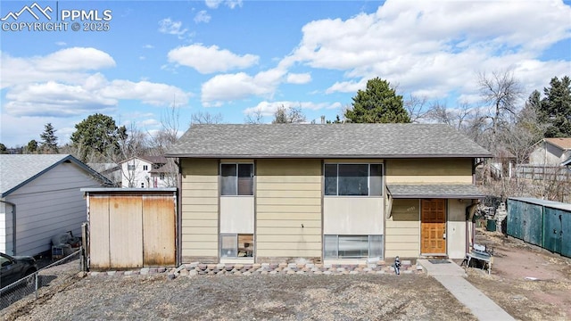 view of front of home with roof with shingles and fence