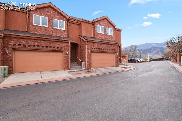 view of front facade featuring a garage, brick siding, a mountain view, and central AC unit