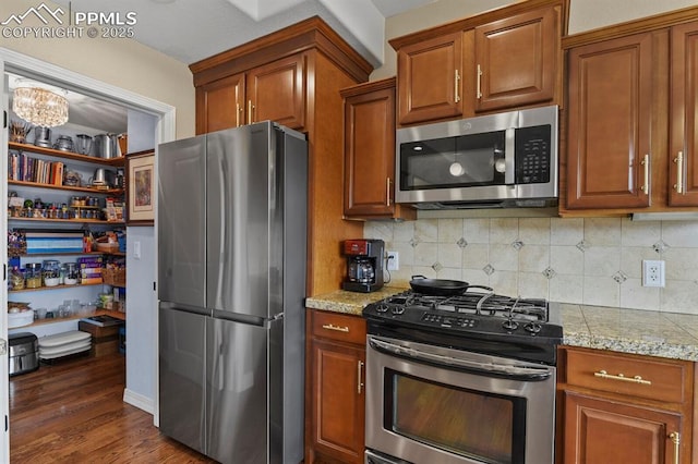 kitchen with dark wood-style floors, stainless steel appliances, tasteful backsplash, and brown cabinets