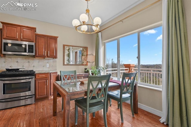 dining room featuring light wood finished floors, baseboards, and a notable chandelier