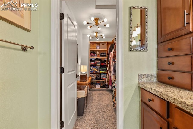 spacious closet with a chandelier and carpet flooring