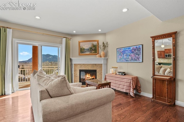 living area with a glass covered fireplace, recessed lighting, wood finished floors, and baseboards