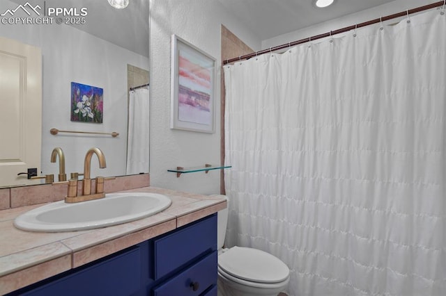 full bath featuring a textured wall, vanity, and toilet