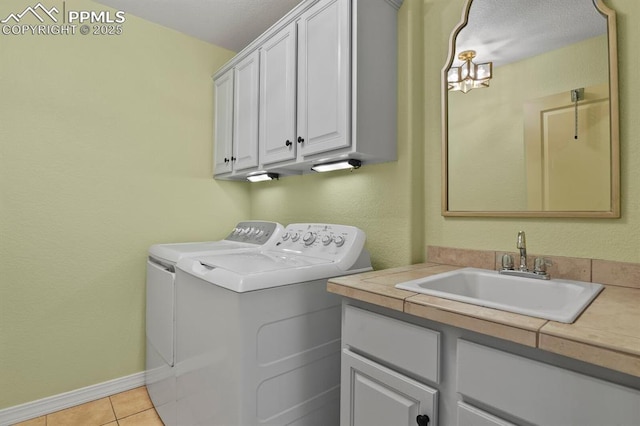 washroom with light tile patterned floors, a sink, baseboards, cabinet space, and washing machine and clothes dryer