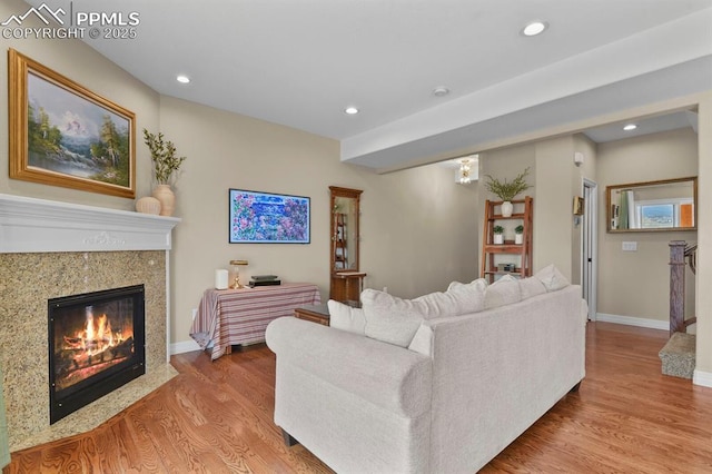 living room with a high end fireplace, baseboards, recessed lighting, and wood finished floors