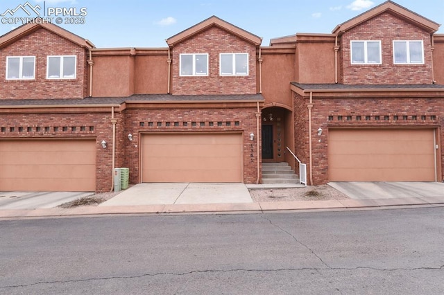 townhome / multi-family property with driveway, a garage, and brick siding