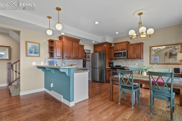 kitchen with a peninsula, appliances with stainless steel finishes, dark wood-style flooring, and backsplash