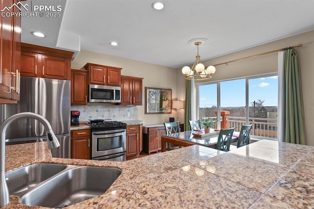 kitchen featuring stainless steel appliances, a sink, backsplash, tile counters, and brown cabinets