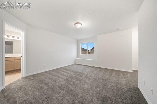 unfurnished bedroom featuring carpet floors, visible vents, baseboards, and ensuite bathroom