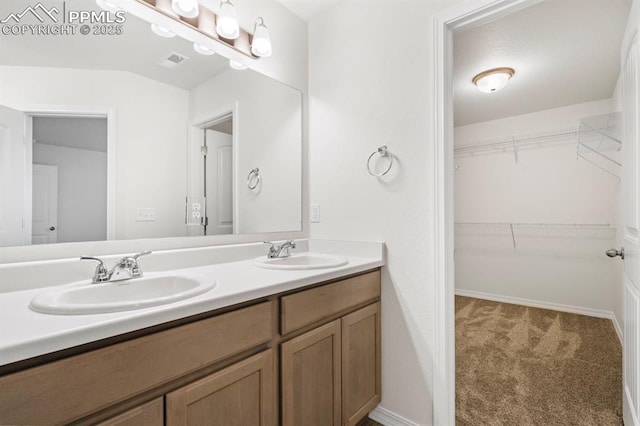 bathroom featuring double vanity, a spacious closet, visible vents, and a sink