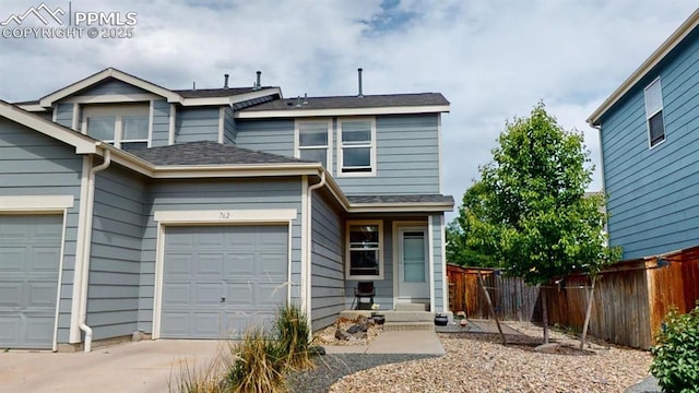 view of front of home featuring concrete driveway, roof with shingles, fence, and an attached garage