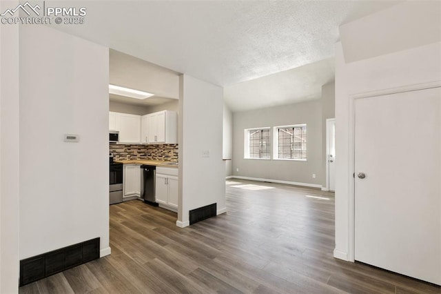 interior space with vaulted ceiling, dark wood-type flooring, a textured ceiling, and baseboards