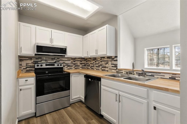 kitchen with decorative backsplash, wood counters, stainless steel appliances, white cabinetry, and a sink