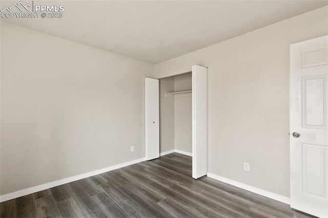 unfurnished bedroom featuring dark wood-style floors, baseboards, and a closet