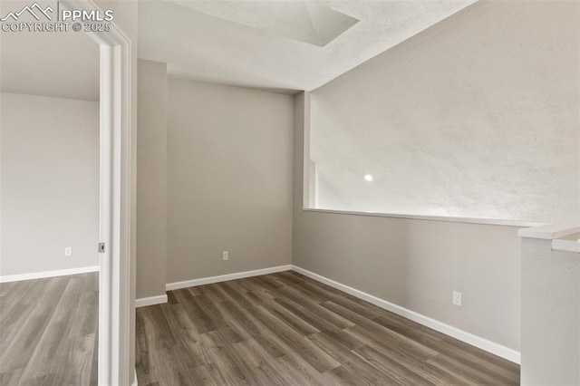 spare room featuring baseboards and wood finished floors