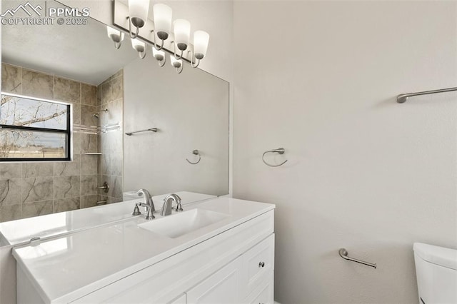 bathroom featuring tiled shower, vanity, and toilet