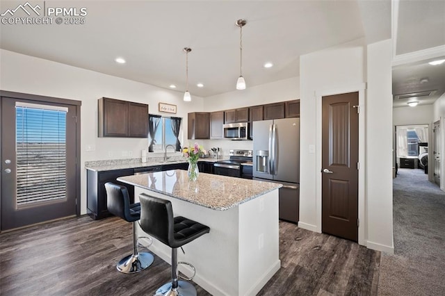 1086 N Purcell Blvd, Pueblo West, CO 81007 - kitchen featuring stainless steel appliances, a kitchen island, a sink, dark brown cabinets, and decorative light fixtures