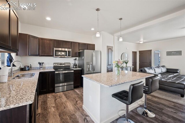 1086 N Purcell Blvd, Pueblo West, CO 81007 - kitchen featuring stainless steel appliances, open floor plan, a sink, a kitchen island, and dark brown cabinets