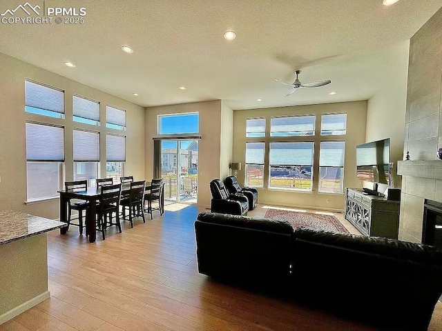 living area with recessed lighting, wood-type flooring, baseboards, and a tiled fireplace