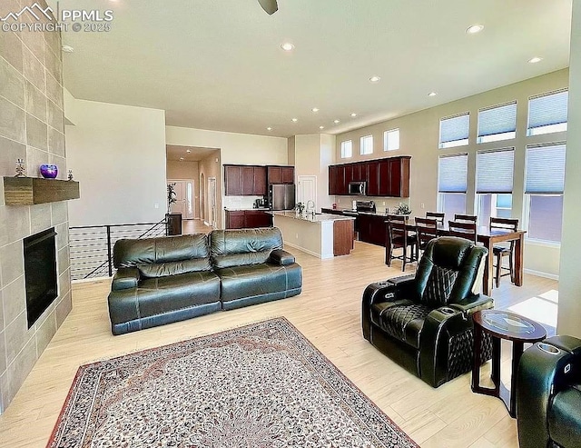 living room featuring light wood-style floors, a tiled fireplace, and recessed lighting