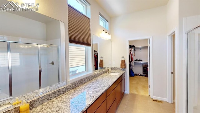 bathroom with a spacious closet, a high ceiling, a stall shower, vanity, and tile patterned flooring