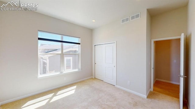 unfurnished bedroom with carpet floors, a closet, visible vents, and baseboards