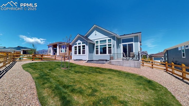 rear view of house featuring a fenced backyard and a lawn