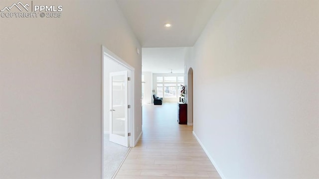 hall with light wood-style floors, arched walkways, baseboards, and recessed lighting