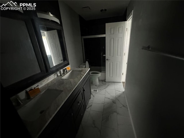 bathroom featuring marble finish floor, double vanity, toilet, an enclosed shower, and a sink