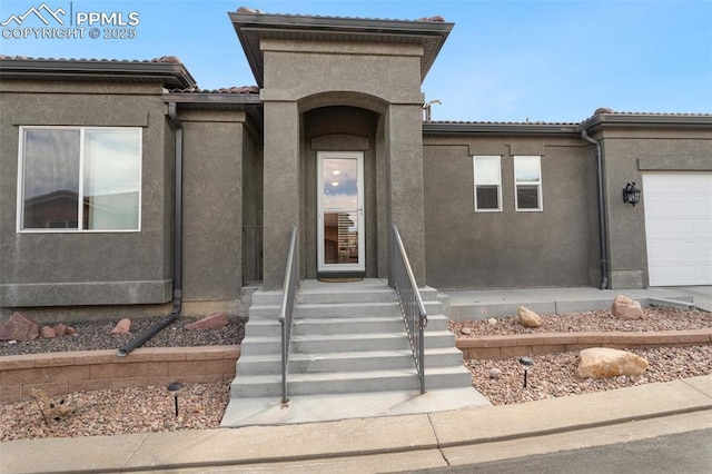 view of front of home featuring a tile roof, an attached garage, and stucco siding