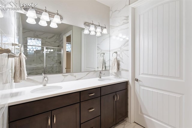 full bathroom featuring marble finish floor, a sink, a shower stall, and double vanity