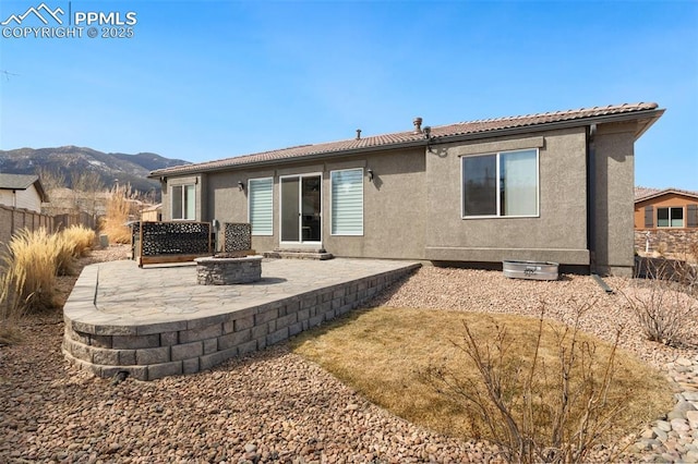 rear view of property with a fire pit, a patio area, a mountain view, and stucco siding