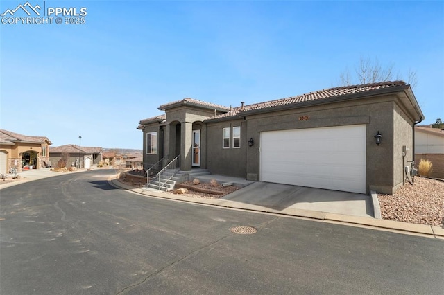 view of front facade with a garage, a tiled roof, concrete driveway, and stucco siding