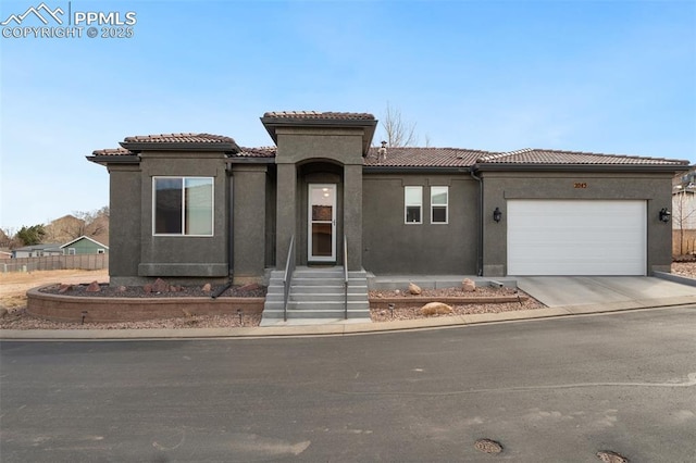 mediterranean / spanish-style home with driveway, stucco siding, a garage, and a tiled roof