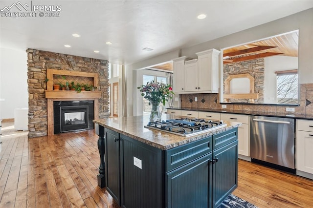 kitchen featuring light wood-style flooring, backsplash, appliances with stainless steel finishes, white cabinets, and plenty of natural light