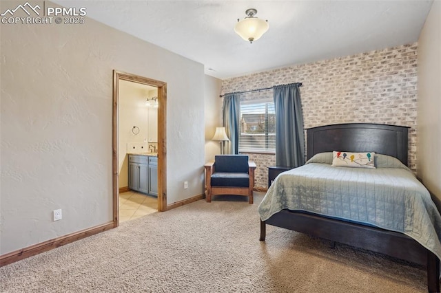 bedroom featuring light carpet, a textured wall, baseboards, and ensuite bathroom