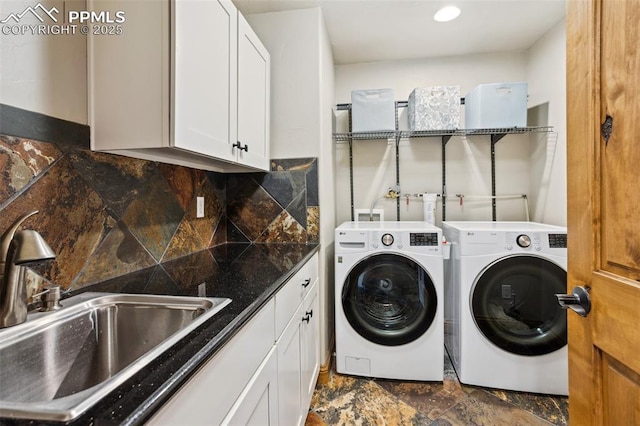 laundry room featuring stone finish floor, cabinet space, a sink, and separate washer and dryer