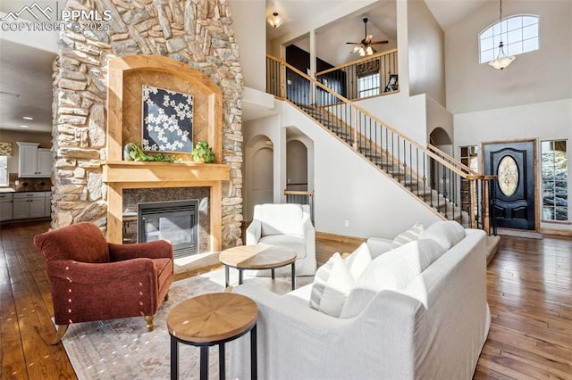 living room featuring stairway, wood-type flooring, arched walkways, and a glass covered fireplace